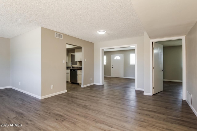unfurnished living room featuring baseboards, visible vents, and dark wood finished floors