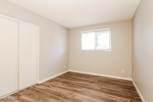 unfurnished bedroom featuring baseboards, light wood-style floors, and a closet