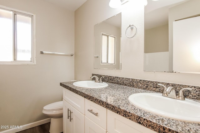 bathroom with wood finished floors, a sink, double vanity, and toilet