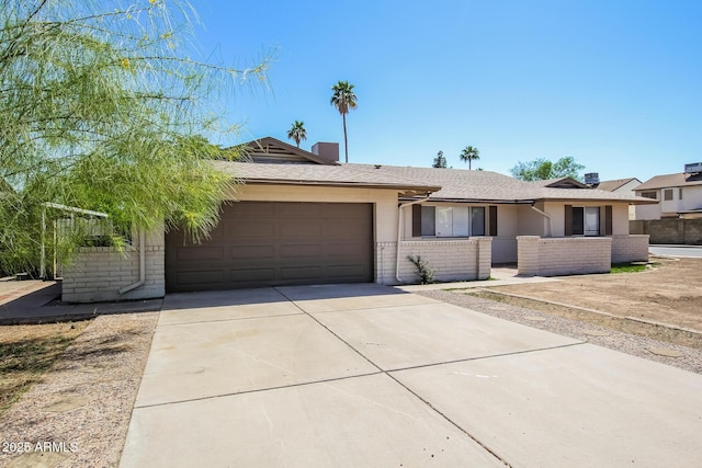 ranch-style house featuring fence, concrete driveway, brick siding, and a garage