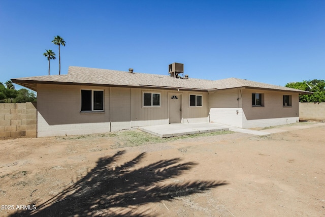 rear view of property with fence and a shingled roof