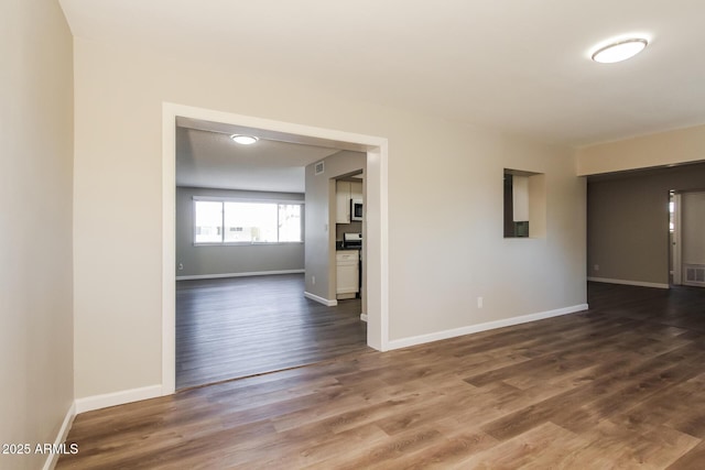 empty room with visible vents, baseboards, and dark wood-type flooring