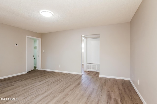 empty room with light wood finished floors, baseboards, and visible vents