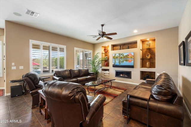 living room with visible vents, a glass covered fireplace, ceiling fan, recessed lighting, and dark tile patterned floors