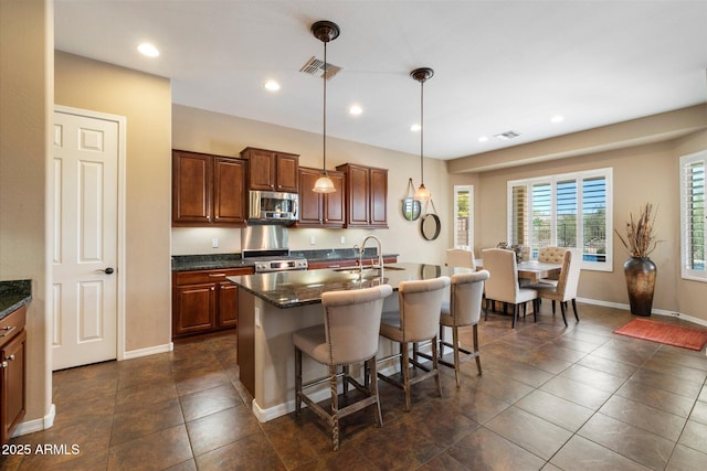 kitchen with visible vents, a sink, a kitchen breakfast bar, and stainless steel appliances