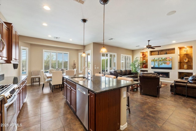 kitchen with ceiling fan, a sink, a breakfast bar, stainless steel appliances, and recessed lighting