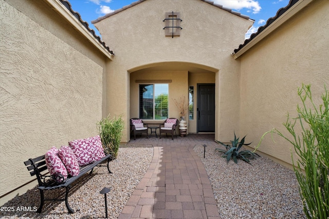 property entrance featuring a patio, stucco siding, and a tiled roof