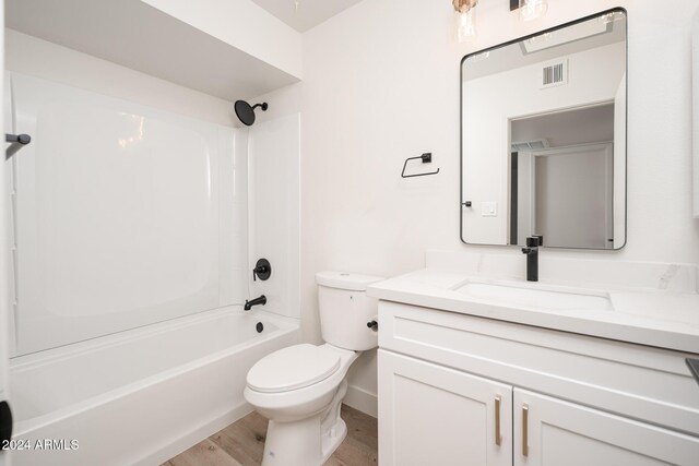 full bathroom featuring toilet, vanity, hardwood / wood-style flooring, and  shower combination