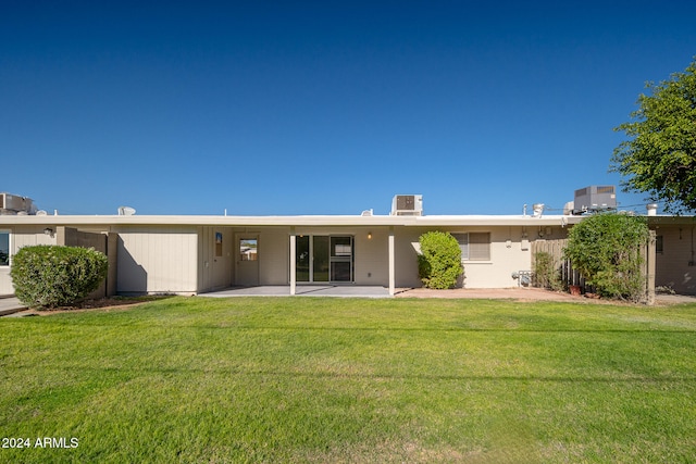 rear view of house with central AC unit, a patio, and a lawn