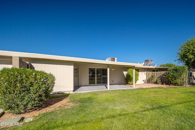 back of house with a lawn and a patio