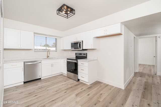 kitchen featuring white cabinetry, stainless steel appliances, sink, and light hardwood / wood-style flooring