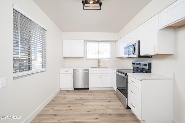 kitchen featuring stainless steel appliances, light hardwood / wood-style floors, white cabinetry, and sink