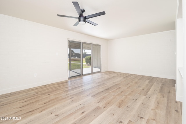 spare room featuring light wood-type flooring, brick wall, and ceiling fan