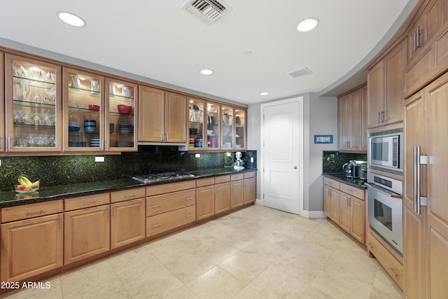 kitchen featuring light tile patterned floors, appliances with stainless steel finishes, dark stone countertops, and decorative backsplash