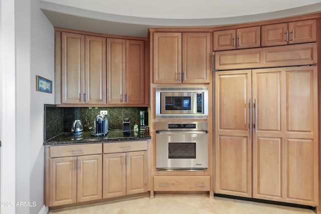 kitchen featuring light tile patterned floors, appliances with stainless steel finishes, decorative backsplash, and dark stone counters