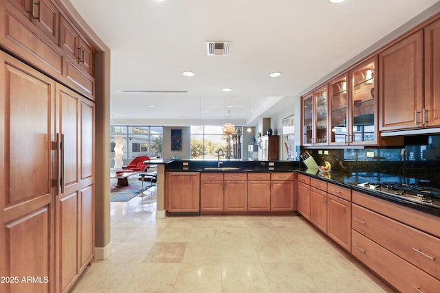 kitchen featuring tasteful backsplash, sink, hanging light fixtures, kitchen peninsula, and stainless steel gas cooktop