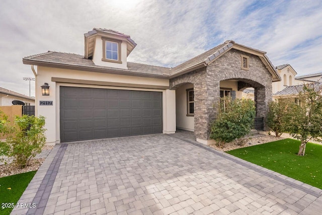 view of front of home featuring decorative driveway, stucco siding, and stone siding