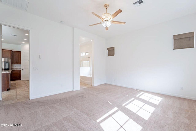 empty room with light colored carpet, visible vents, ceiling fan, and baseboards