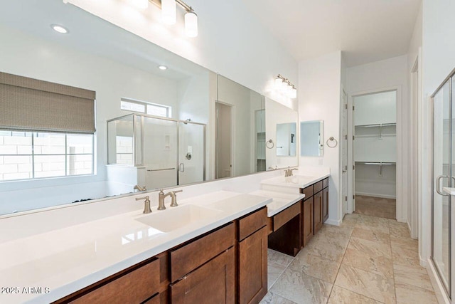 full bath featuring a shower stall, double vanity, marble finish floor, and a sink