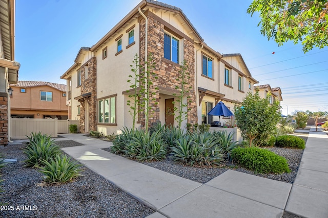 exterior space featuring stone siding, fence, and stucco siding