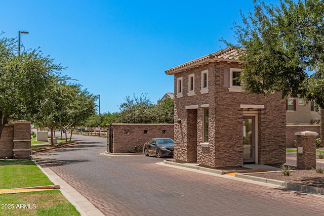 view of decorative road featuring curbs and a gated entry