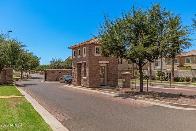 view of asphalt road with curbs and a gated entry