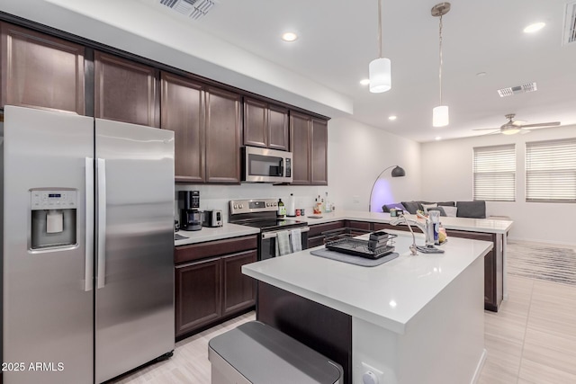 kitchen featuring appliances with stainless steel finishes, dark brown cabinets, light countertops, a peninsula, and recessed lighting