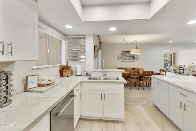 kitchen featuring light stone counters, a sink, stainless steel dishwasher, white cabinets, and recessed lighting