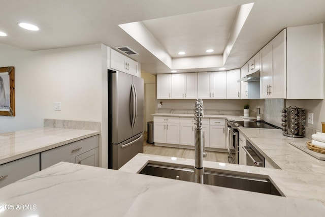 kitchen featuring under cabinet range hood, visible vents, white cabinets, light stone countertops, and appliances with stainless steel finishes