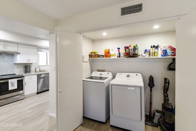 laundry area with light wood-type flooring, laundry area, separate washer and dryer, and visible vents