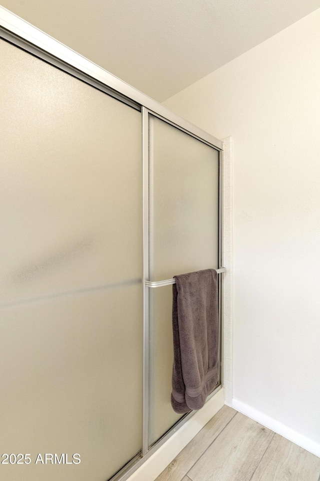 bathroom with an enclosed shower and wood finished floors