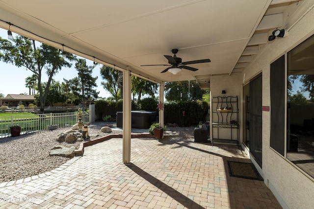 view of patio with fence, ceiling fan, and a hot tub