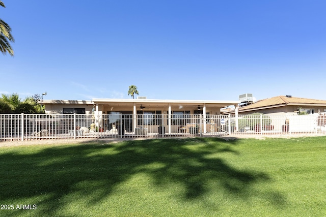 rear view of house featuring ceiling fan, fence, and a yard