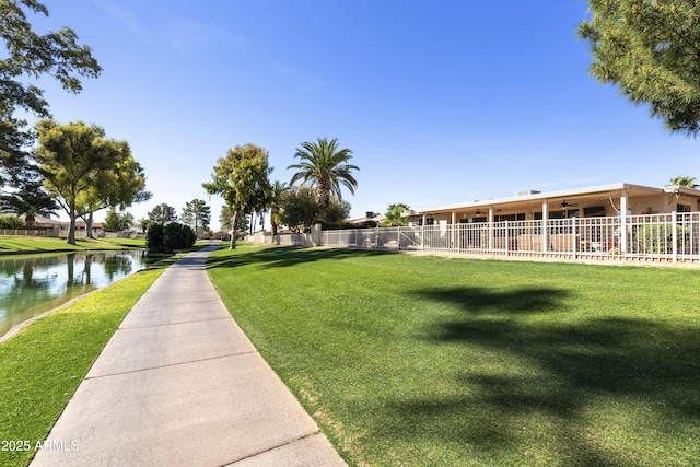 surrounding community featuring a lawn, a water view, and fence
