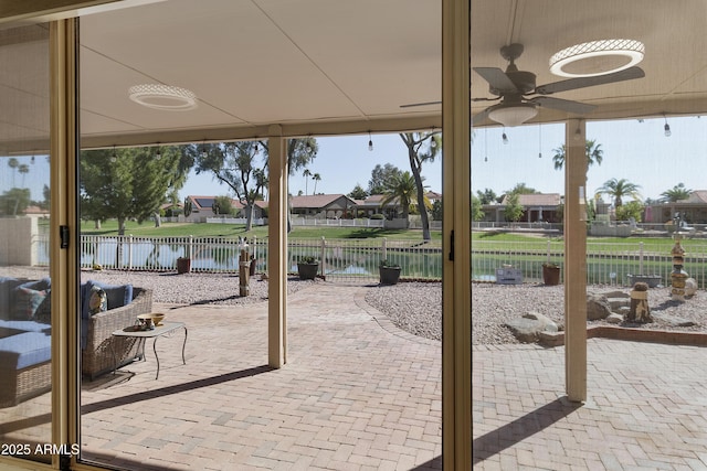 view of patio featuring a water view, fence, and ceiling fan