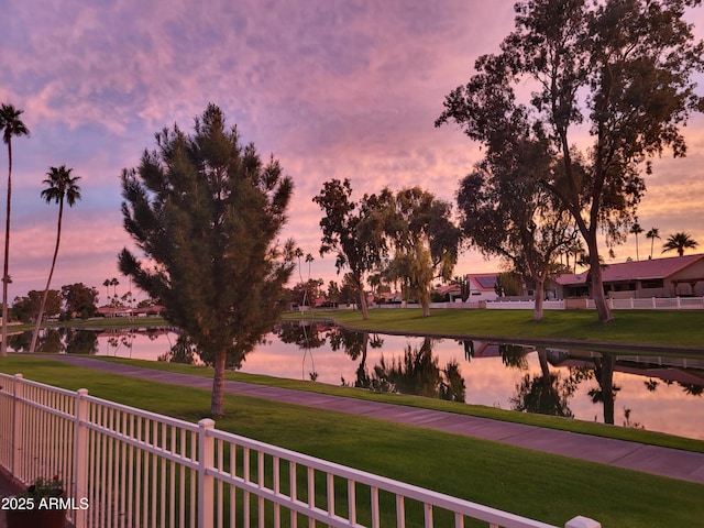 surrounding community with a yard, a water view, and fence