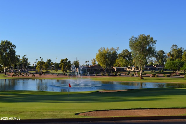 view of home's community with golf course view, a water view, and a lawn