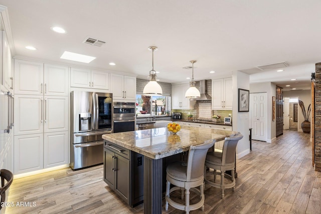 7510 E Larkspur Dr, Scottsdale, AZ 85260 - kitchen featuring stainless steel appliances, a center island, white cabinets, wall chimney exhaust hood, and recessed lighting