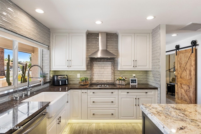 7510 E Larkspur Dr, Scottsdale, AZ 85260 - kitchen with wall chimney exhaust hood, dark stone countertops, backsplash, a sink, and white cabinetry