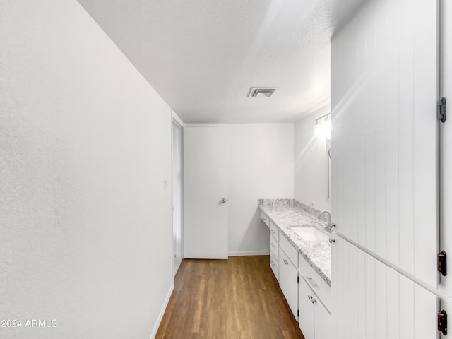 bathroom featuring vanity, wood-type flooring, and a textured ceiling