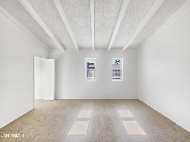 spare room with beam ceiling and light colored carpet