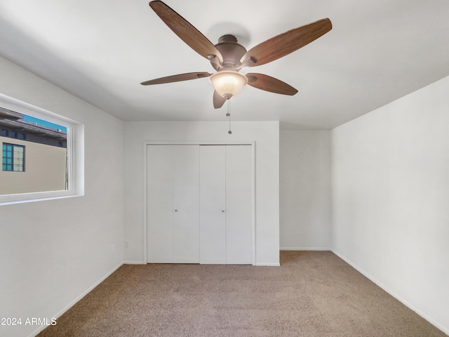 unfurnished bedroom featuring ceiling fan, a closet, and light colored carpet