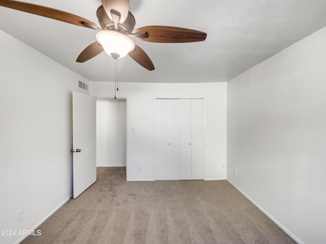 unfurnished bedroom featuring ceiling fan, a closet, and light colored carpet