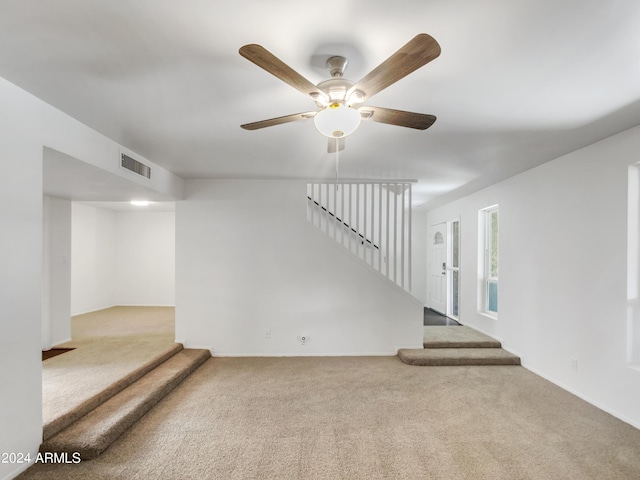 interior space with ceiling fan and light colored carpet