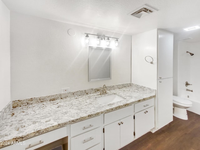 full bathroom featuring tub / shower combination, hardwood / wood-style floors, a textured ceiling, toilet, and vanity