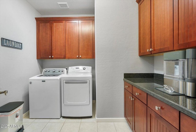 clothes washing area with cabinets, light tile patterned flooring, and washing machine and clothes dryer