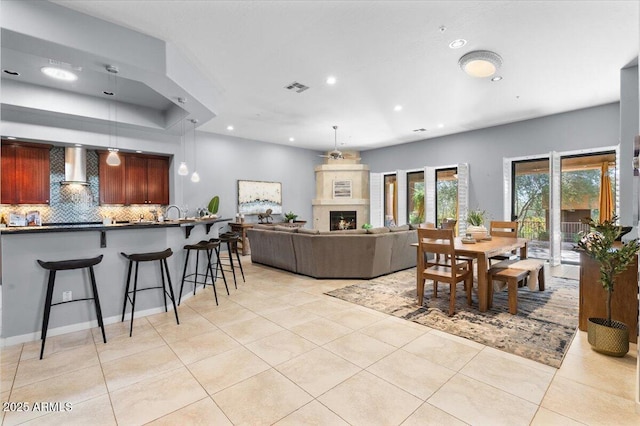 dining space with a large fireplace and light tile patterned flooring