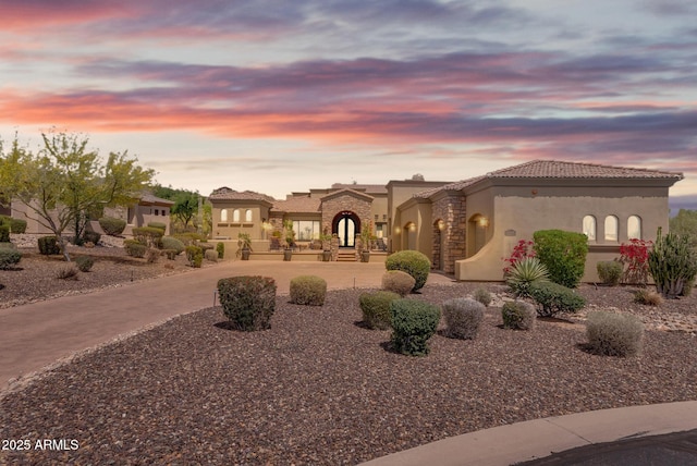 3217 N Piedra Cir, Mesa, AZ 85207 - mediterranean / spanish house with stucco siding, stone siding, a tiled roof, and curved driveway