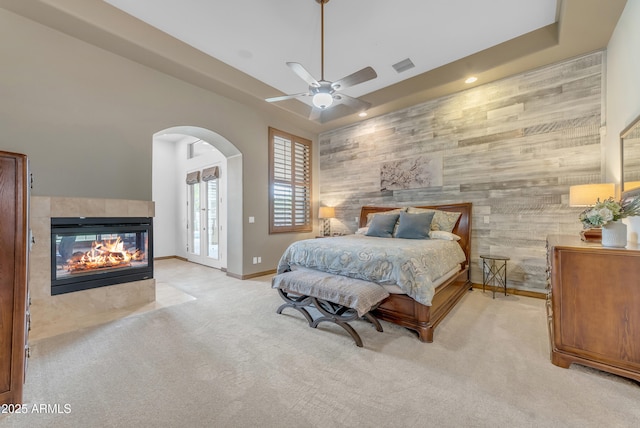 3217 N Piedra Cir, Mesa, AZ 85207 - carpeted bedroom with an accent wall, a tiled fireplace, arched walkways, wooden walls, and baseboards
