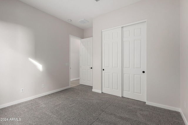 unfurnished bedroom with dark colored carpet and a closet